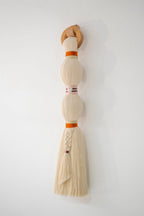 Decorative broom with a wooden handle and white bristles on a white wall