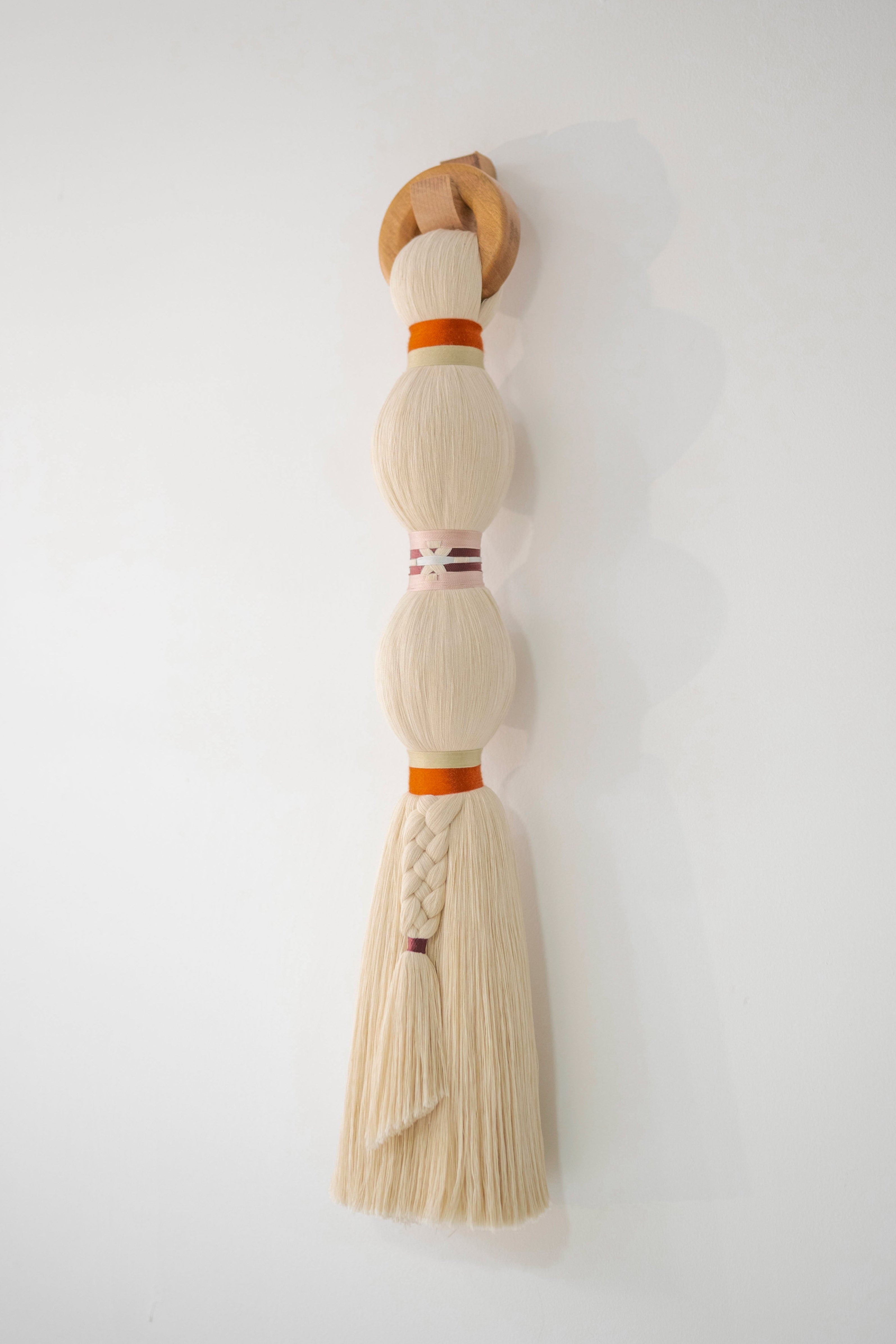 Decorative broom with a wooden handle and white bristles on a white wall